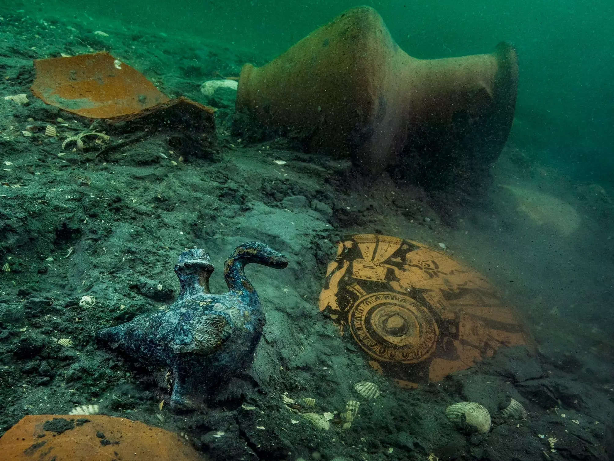 A picture shows a Grecian vase, bronze shield, buried in mud underwater.