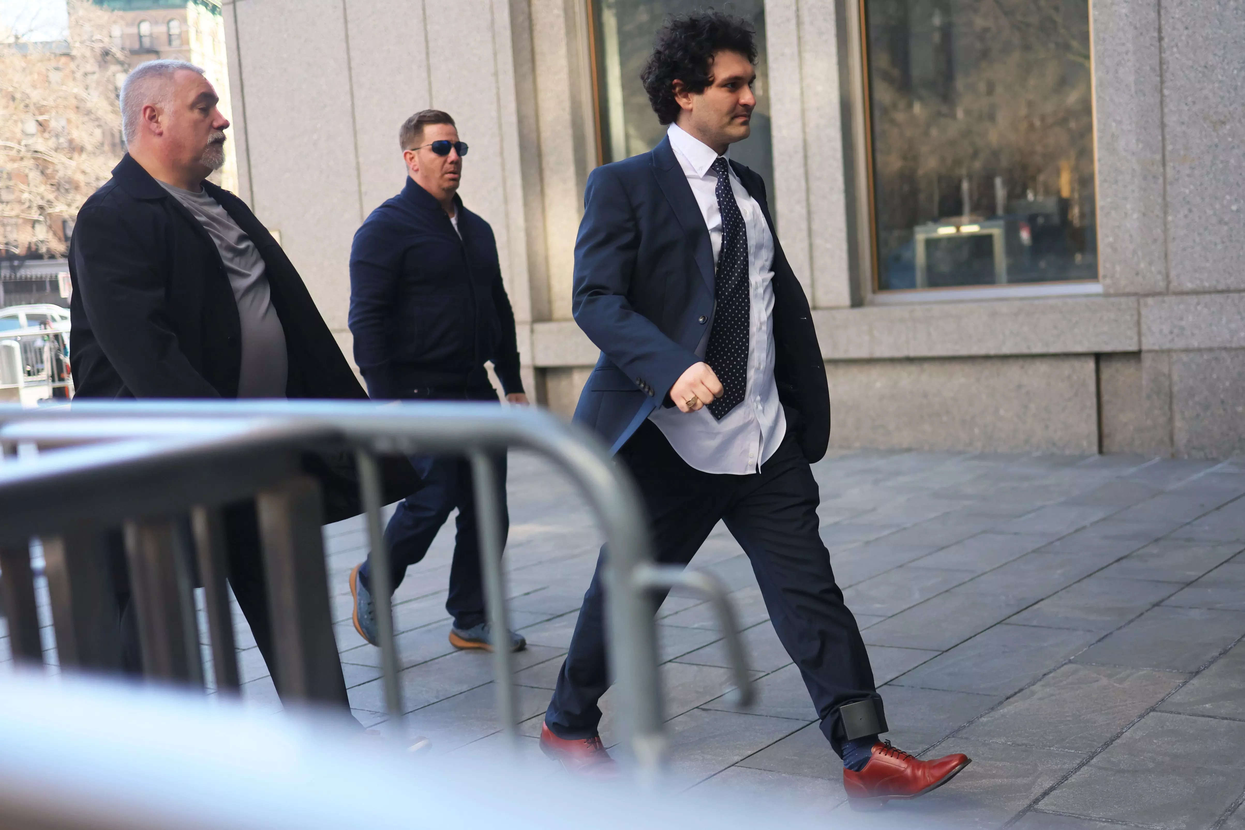 FTX Founder Sam Bankman-Fried arrives at Manhattan Federal Court for a court appearance on March 30, 2023, with his shirt untucked and an ankle tag.