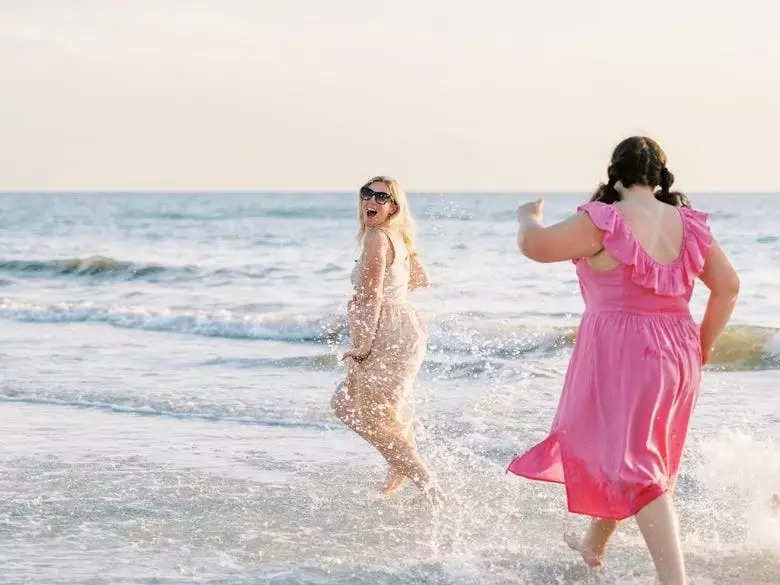 A blond woman and a brunette preteen at the beach, playing in the waves