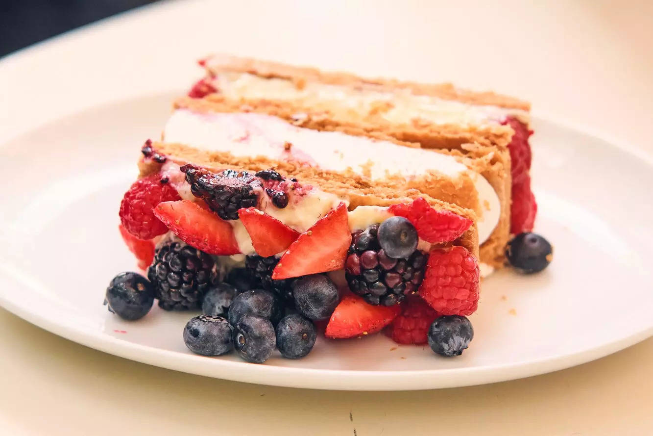 A flaky pastry filled with two layers of cream and topped with strawberries, blueberries, raspberries, and blackberries. 