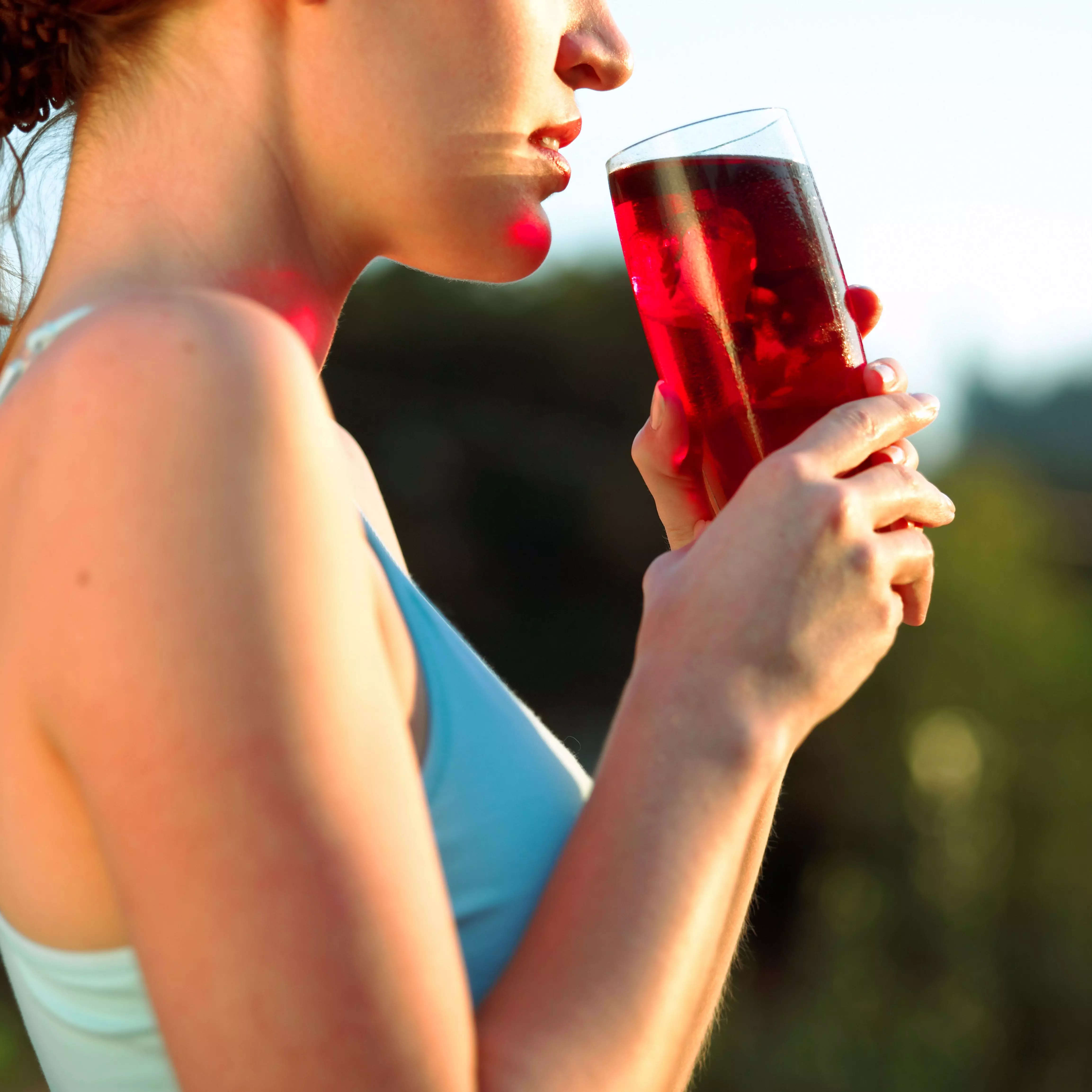A woman holds a glass of cranberry juice.
