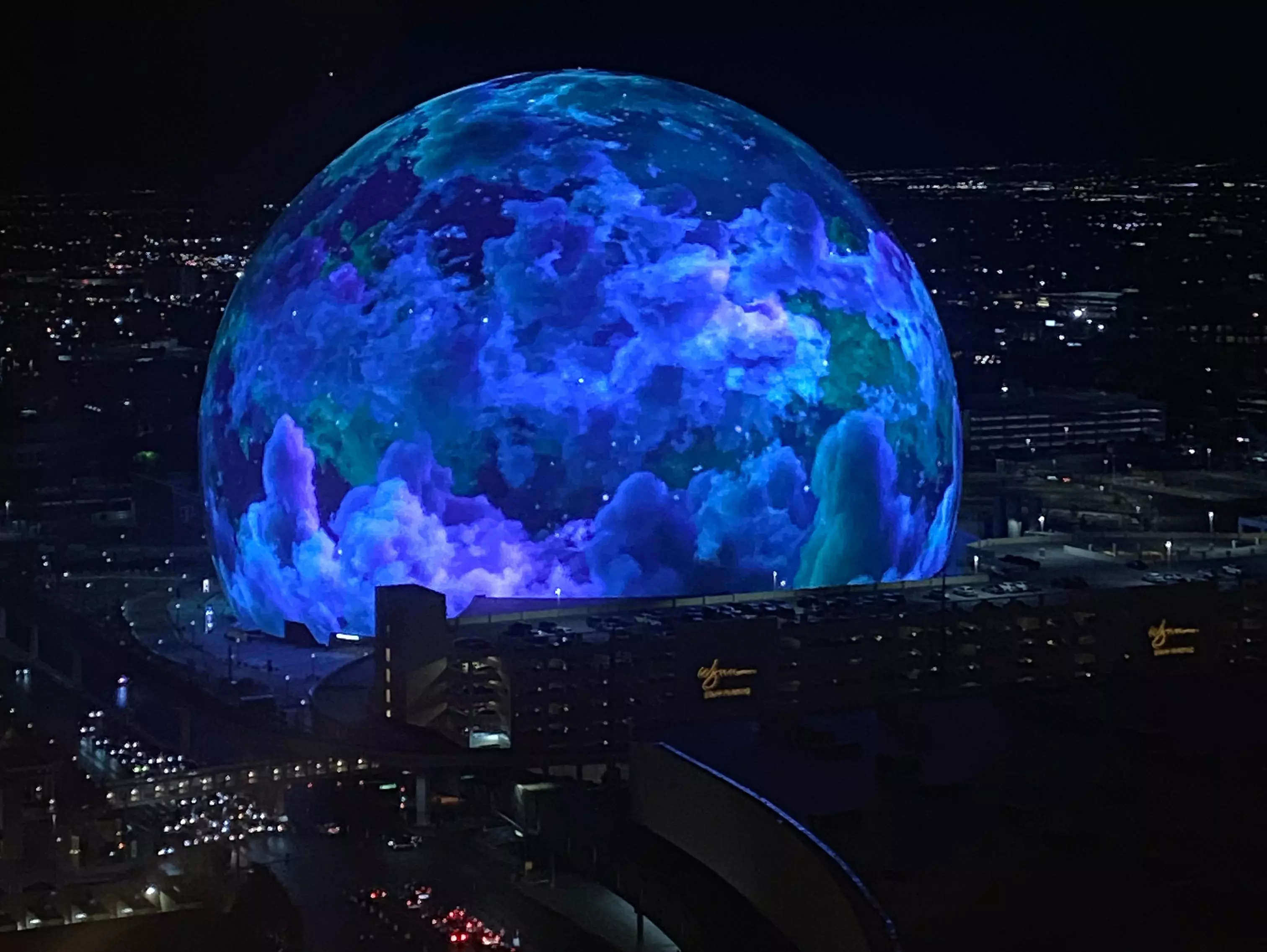the sphere in las vegas lit up with blue, purple, and green lights at night