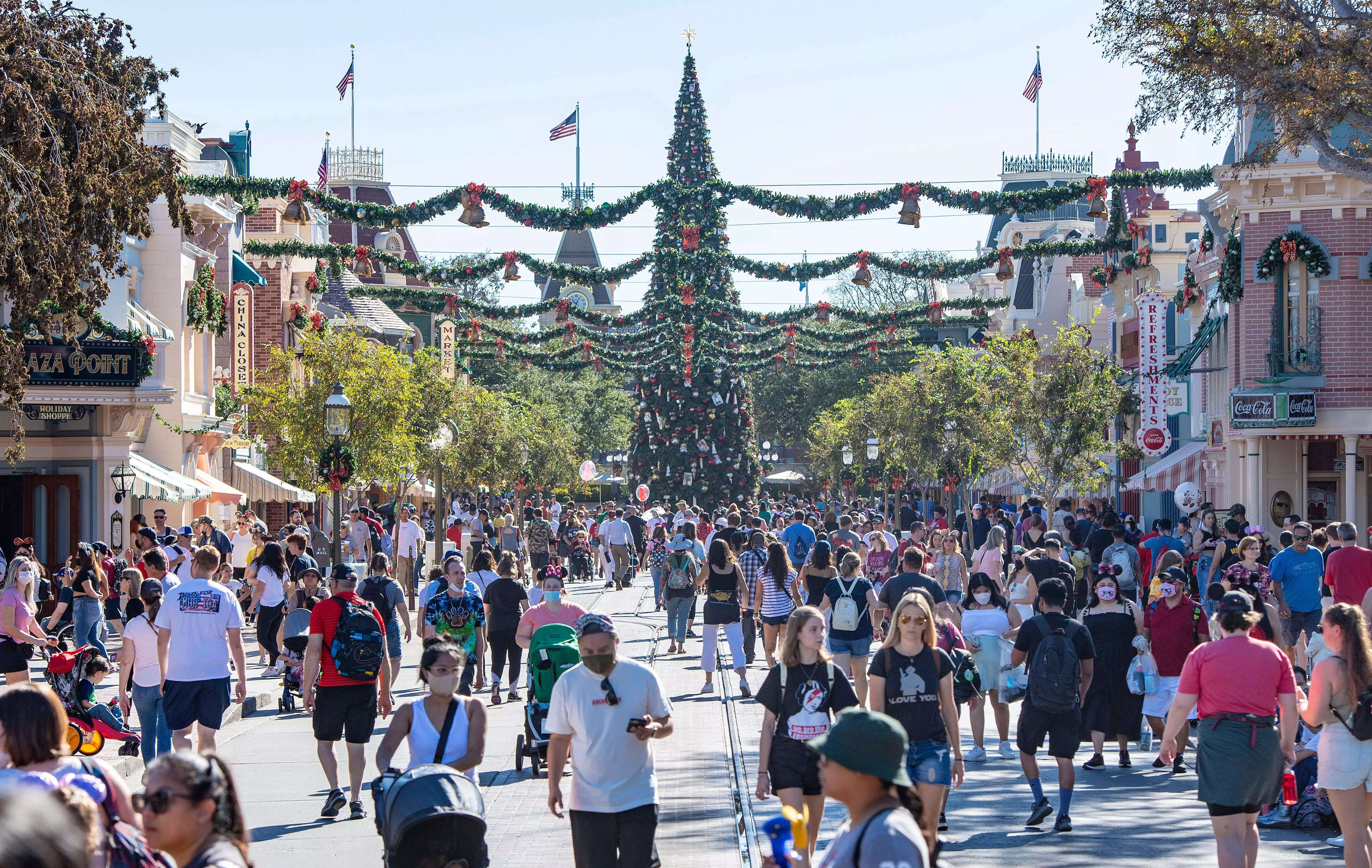 Holiday decorations hang from the buildings as a large Christmas tree towers above visitors while they make their way along Main Street USA.