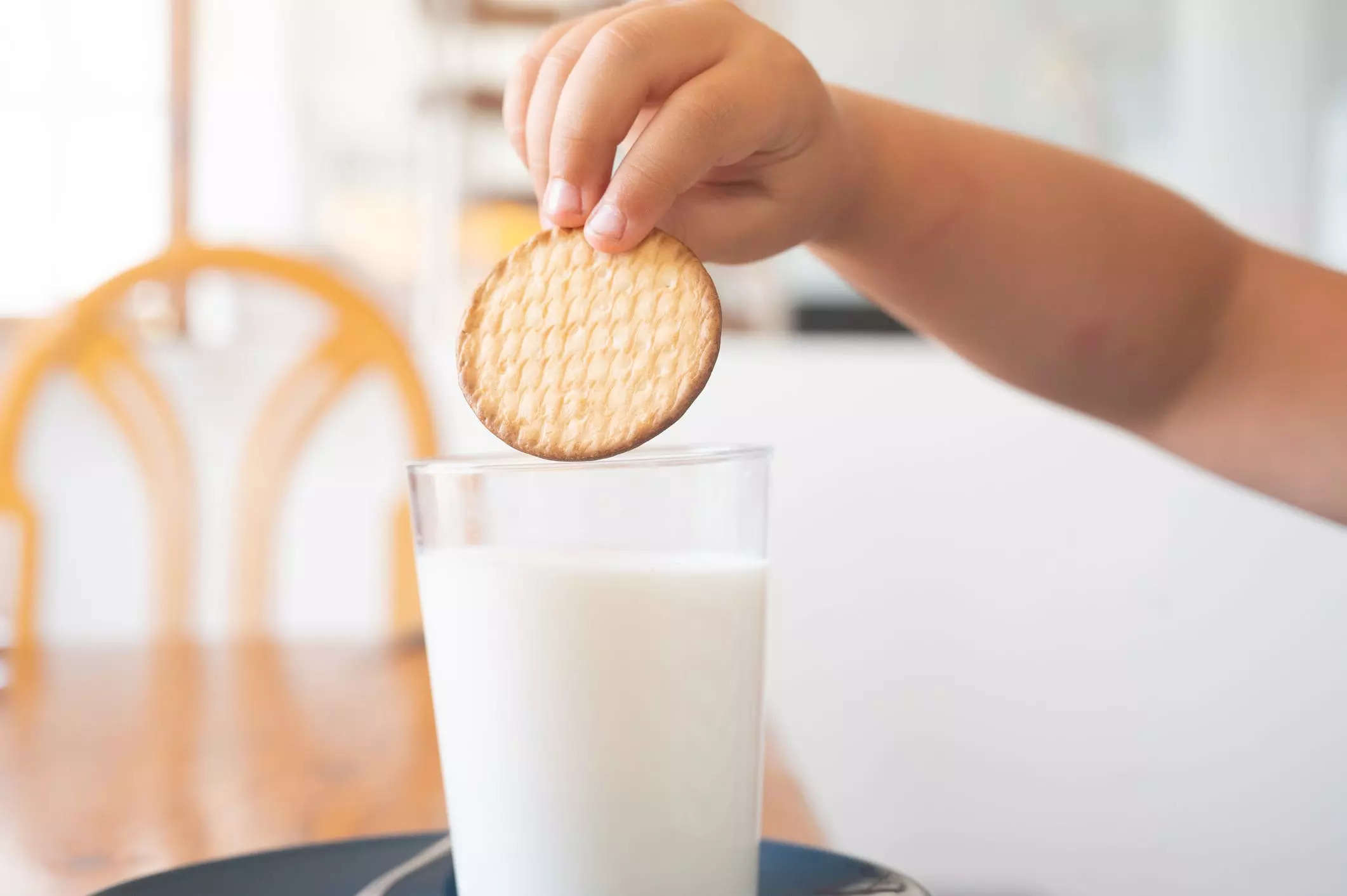 A child dunking a cookie in a glass of milk.