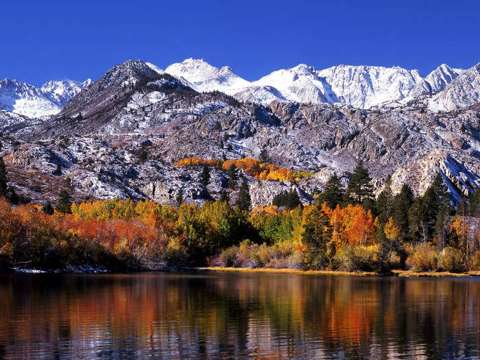 Bishop Creek Canyon is home to rocky, snow-capped mountains in the distance, and foliage in shades of reds, oranges, and yellows.