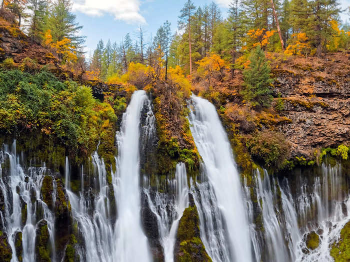 At McArthur-Burney Falls Memorial State Park, the leaves surrounding the waterfalls turn shades of orange and yellow in the fall.