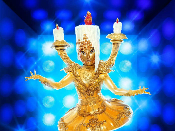 The Candelabra wears a golden dress and contains three candles.