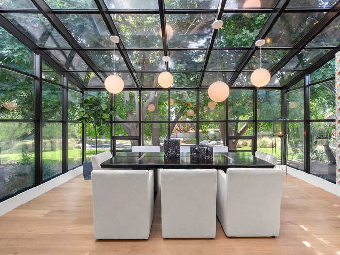 A glass atrium dining area overlooks "expansive meadows, mature trees, and a large free-form pool," per the listing.