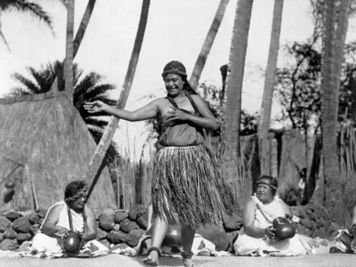 1924: A native Hawaiian dancer performs while other women keep rhythm with gourds.