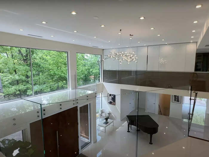 Back in the open hallway atop the stairs, huge windows above the front door offer a peek of the driveway, while the clear banister allows for easy viewing of the foyer below.