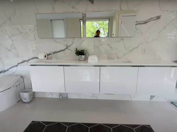 Behind the shower is a floating double vanity and a toilet with a lid that raises with the wave of a hand.