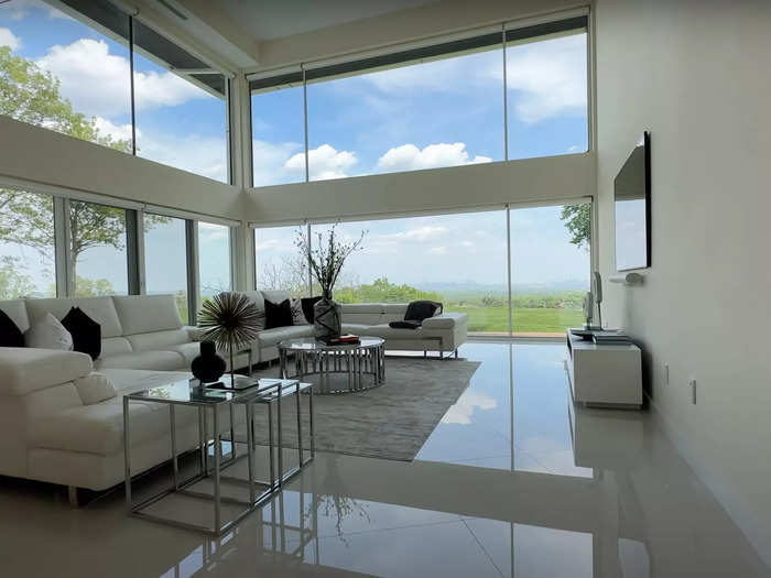 The living room, just a few steps to the right of the front door, boasts two stories of windows overlooking the backyard...