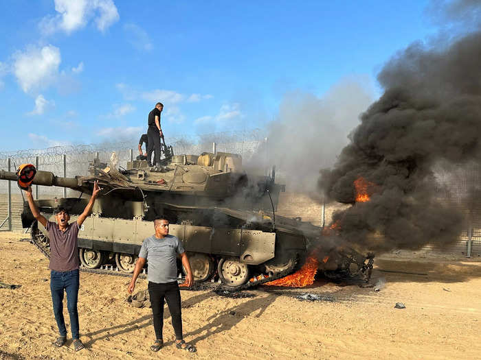 8. Palestinians in front of a burning Israeli tanks after it was captured by Palestinian gunmen.