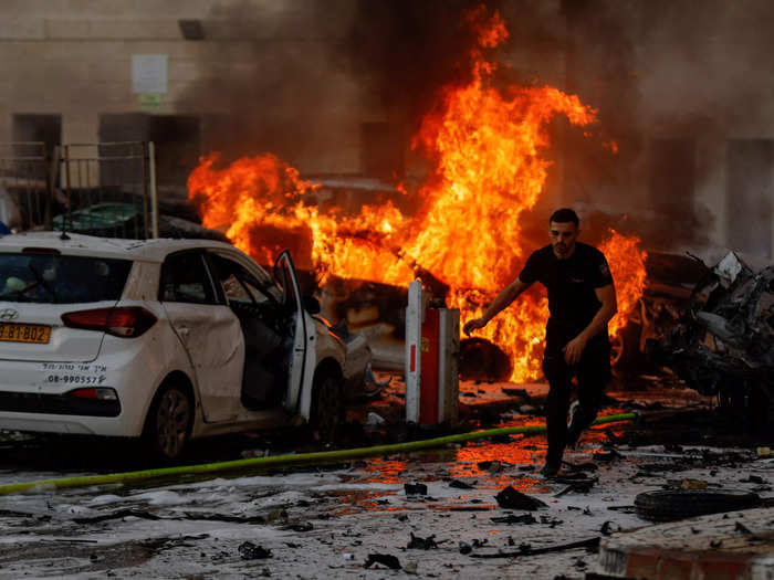 4. A man running as cars a set ablaze fire following Hamas rocket attacks in Ashkelon Israel.