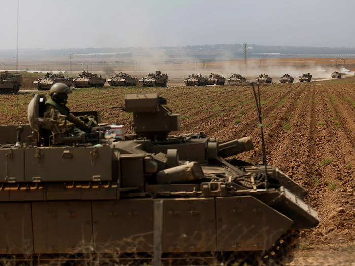 A caravan of Israeli armored vehicles moves along a road amid farms near the Gaza border