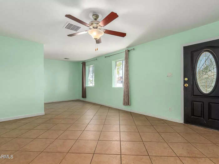 The living room has a sea green wall and tan-colored tile flooring.