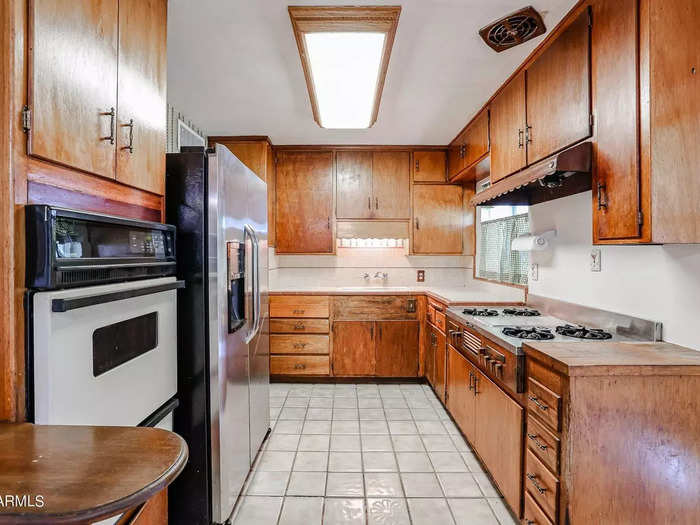 The kitchen has dark wood cabinets and a tiled floor.