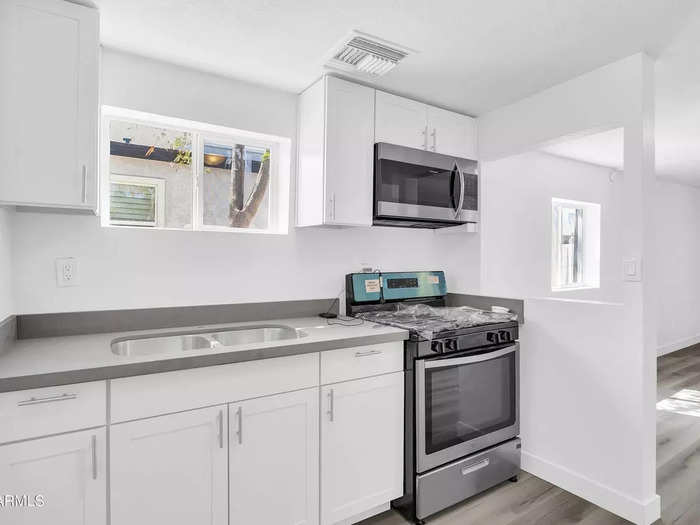 The kitchen has bright white walls and cabinets — showing the obvious updates after a flipper purchased the older home.