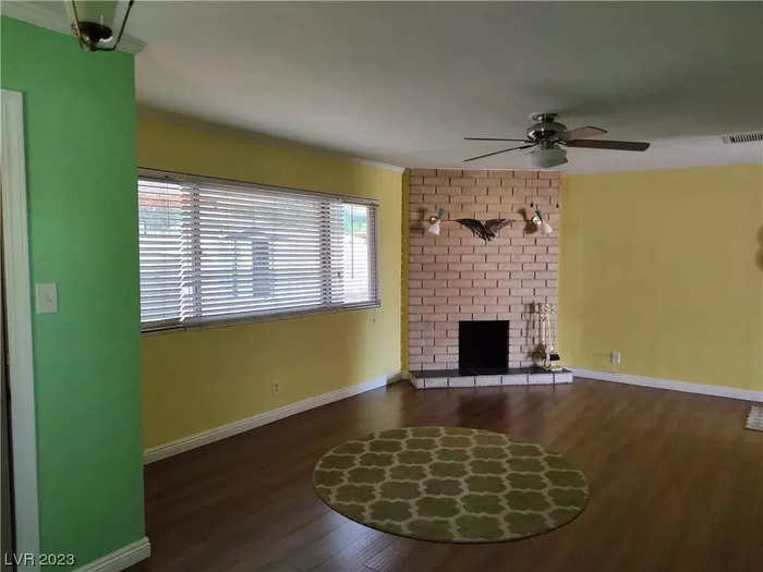 The living room features a ceiling fan, fireplace, and colorful green and yellow walls.