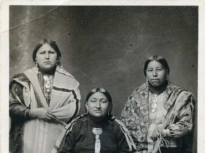 Circa 1918: Three Osage women sit for a portrait in traditional Osage attire.