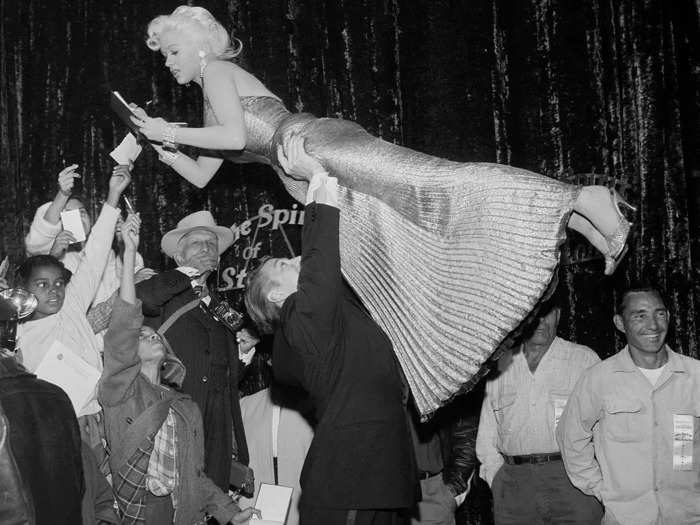 Actress Jayne Mansfield gracefully signed autographs while being lifted by Mickey Hargitay at the "Spirit of St. Louis" premiere.