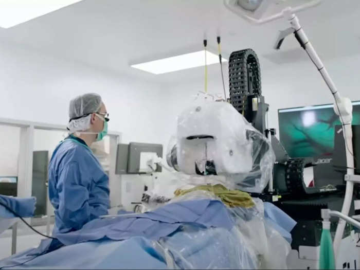 Before the robot can insert the device, a human surgeon must remove a portion of the individual