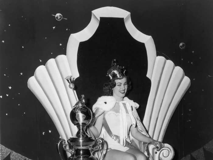 July 17, 1953: Christiane Martel, Miss France, sits atop a throne with a trophy and scepter after being crowned Miss Universe.