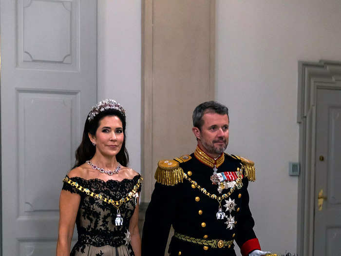 At a birthday gala for Queen Margarethe in 2022, Mary wore an off-the-shoulder ballgown with a sheer overlay and accessorized with a diamond tiara, a chunky gemstone necklace, and a coordinating bracelet.