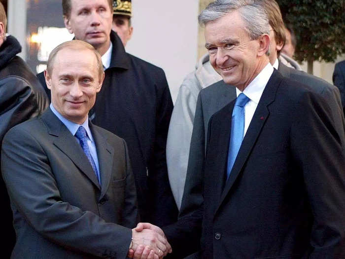 Arnault can be seen shaking hands with Vladimir Putin during the Russian president