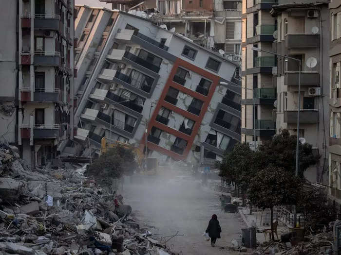 A woman walked on a street amid destroyed buildings after two earthquakes in Hatay, Turkey, in February.