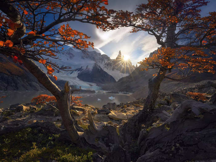 In El Chalten, Patagonia, he took a photo of the sun streaming through trees from behind snow-covered mountain ranges.