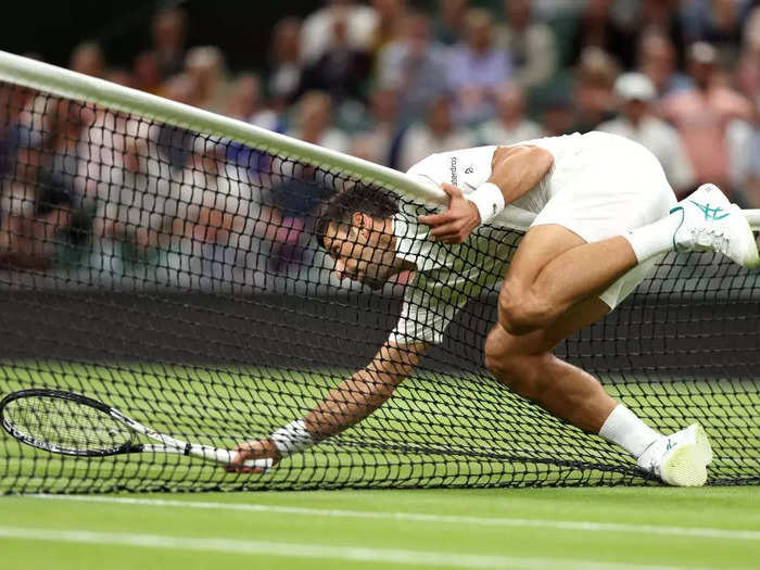 Novak Djokovic of Serbia falls over the net at Wimbledon in London, England, on July 9.