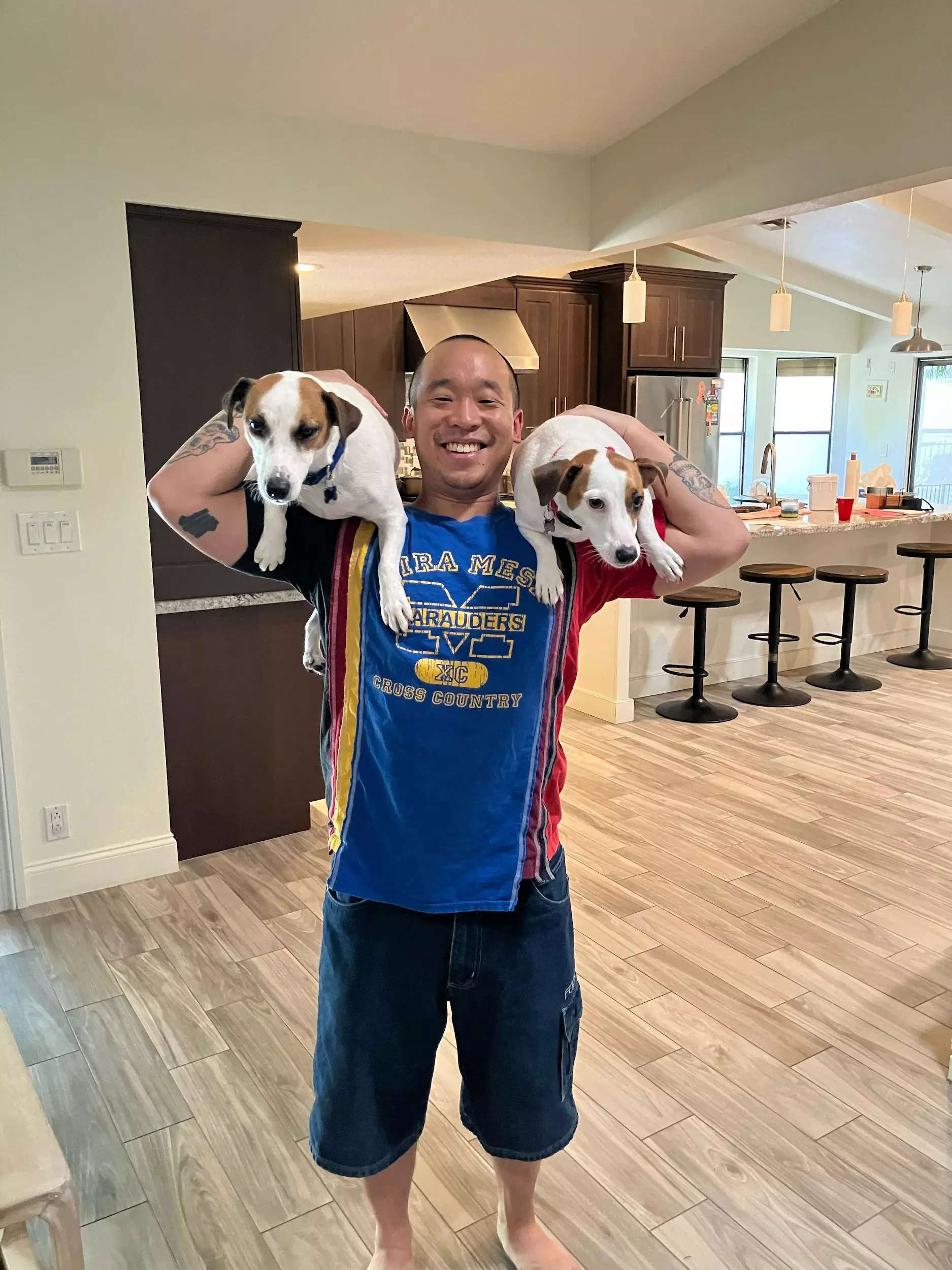 A man holding two dogs inside of his home.