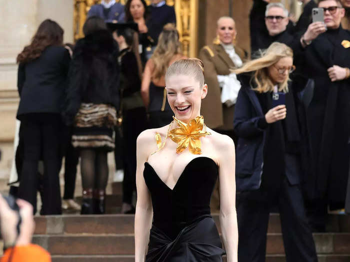 Hunter Schafer wore an asymmetrical dress with a daring neckline and a gold 3D flower necklace.  