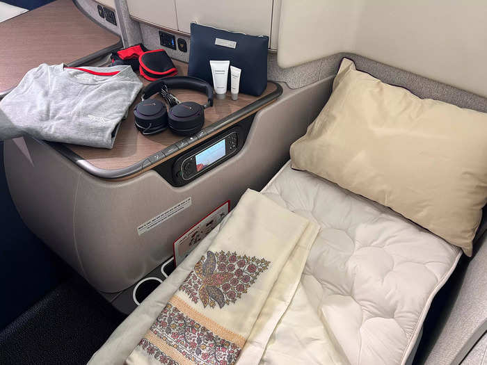 The lie-flat bed has plush linens, headphones, an amenity kit, and pajamas for added comfort.