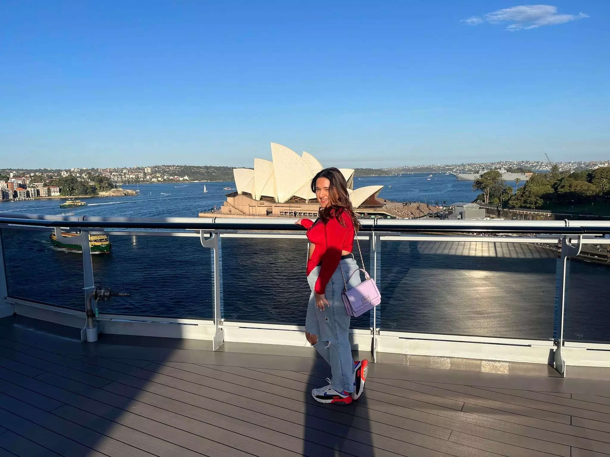 A woman stands in front of the Sydney Opera House