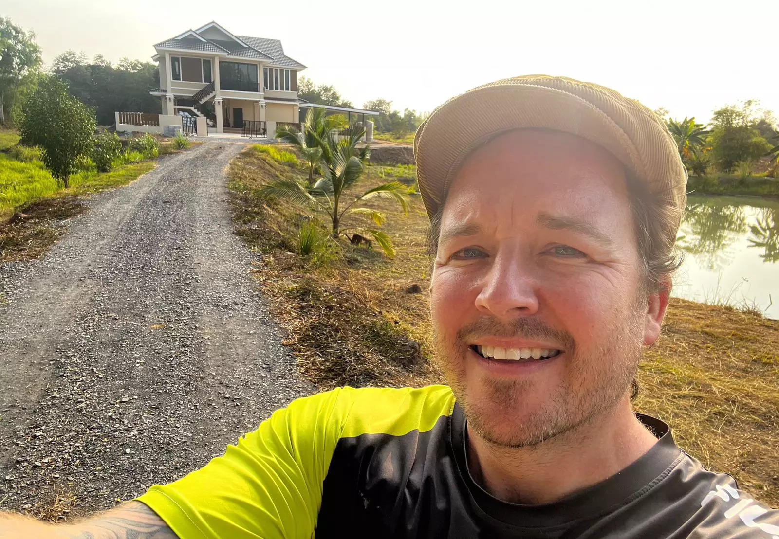 A man posing with his house in the background.