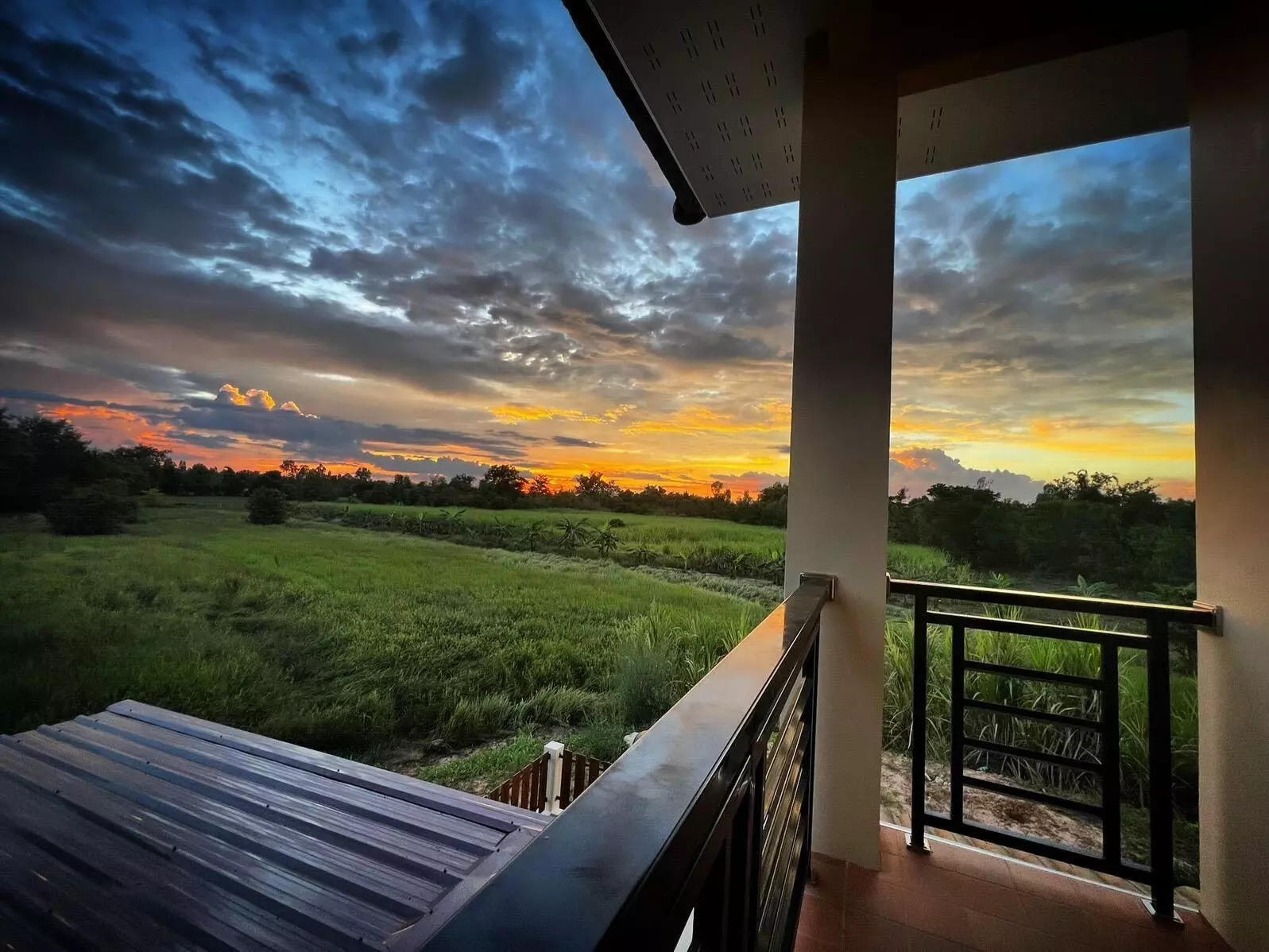 A sunset as viewed from the balcony of a home.