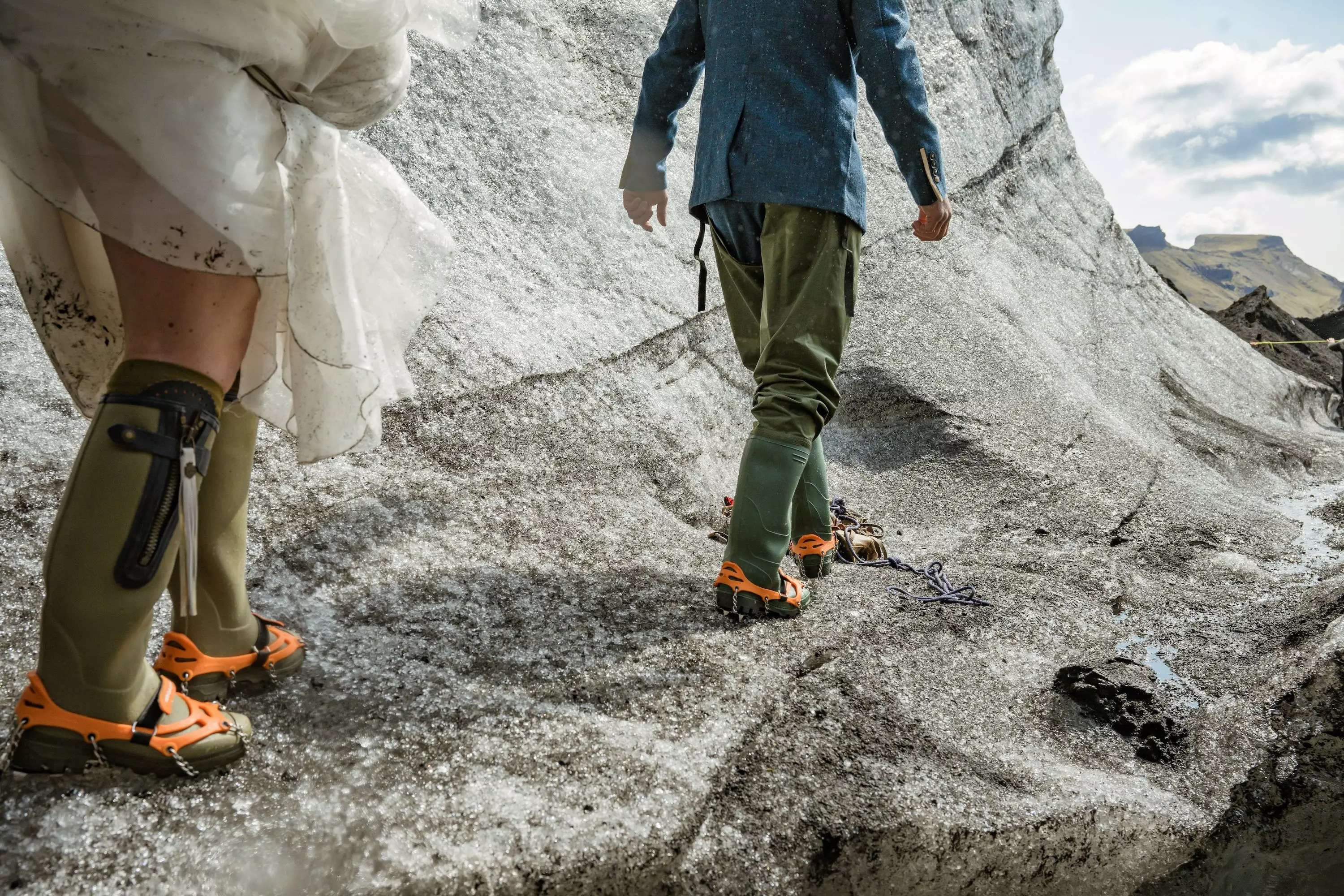 A bride and groom walking on a glacier in Iceland wearing crampons