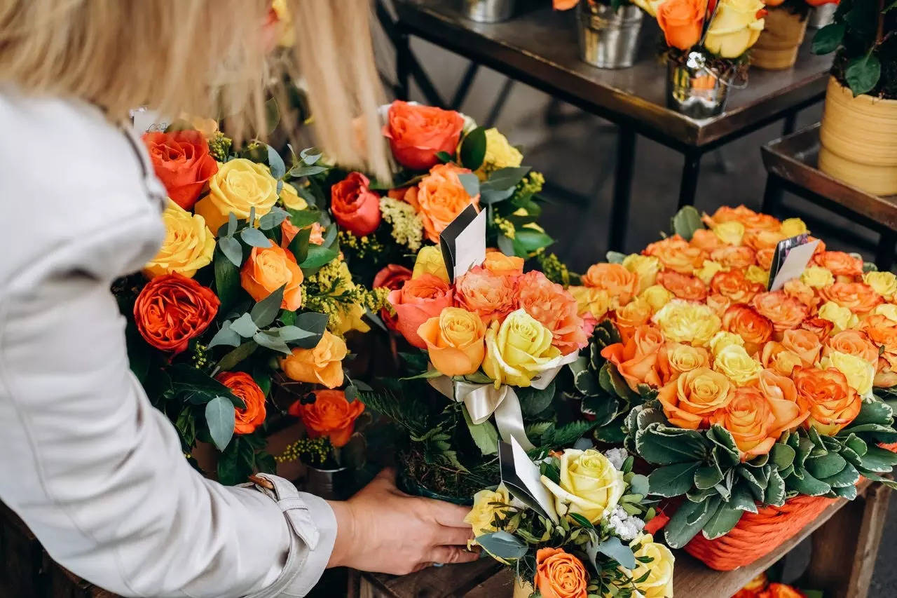 Woman placing vase of orange roses on shelf