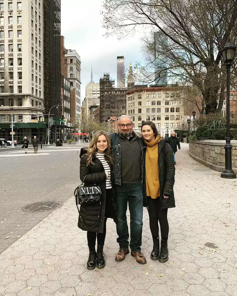 Rachel Volk standing next to her father and sister on a street in New York City. Buildings are visible behind them.