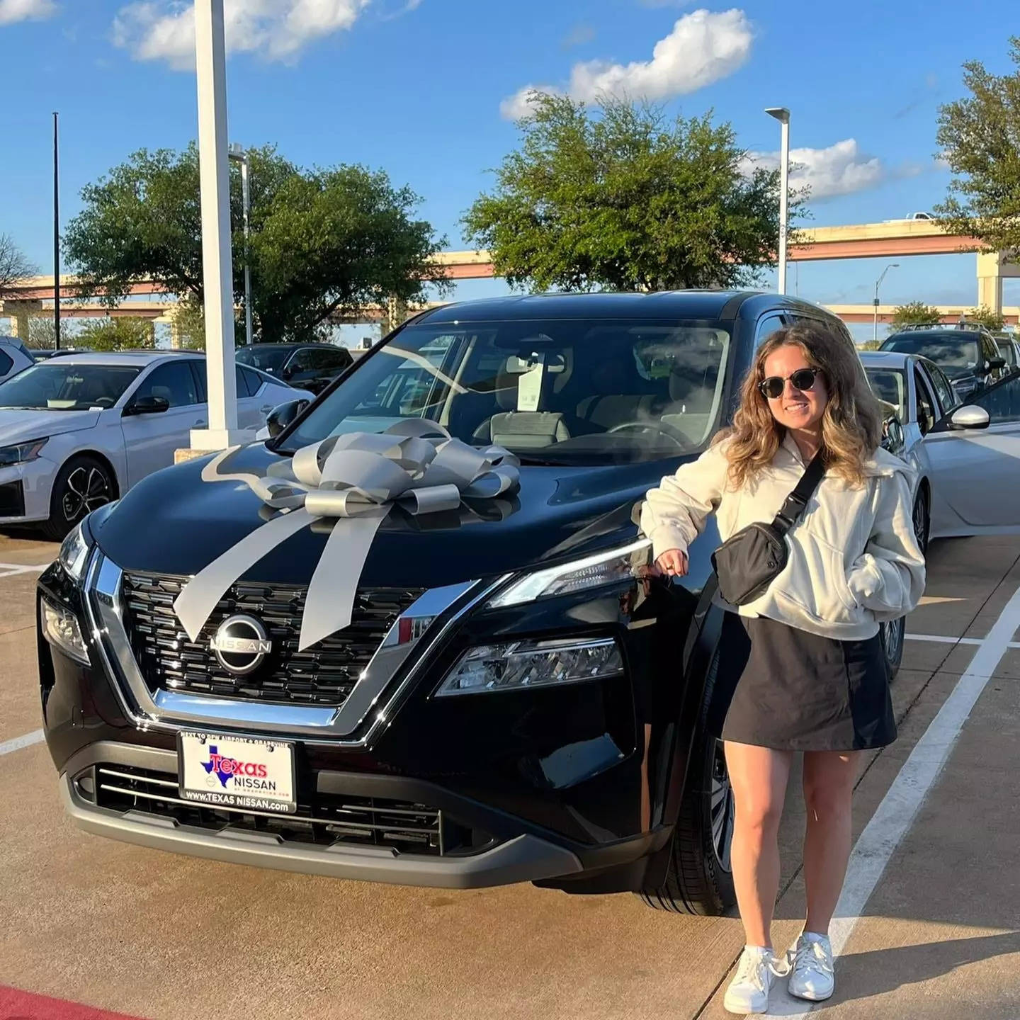 Rachel Volk standing next to a black Nissan car.