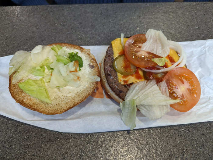 The same burger in the UK had a generous amount of toppings, including four pickles, two slices of tomato, onion slices, and a slathering of cheese, lettuce, and ketchup.