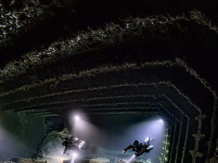 Rows of silt-covered motorbikes, never to be ridden, are seen inside a WW2 cargo steamship.