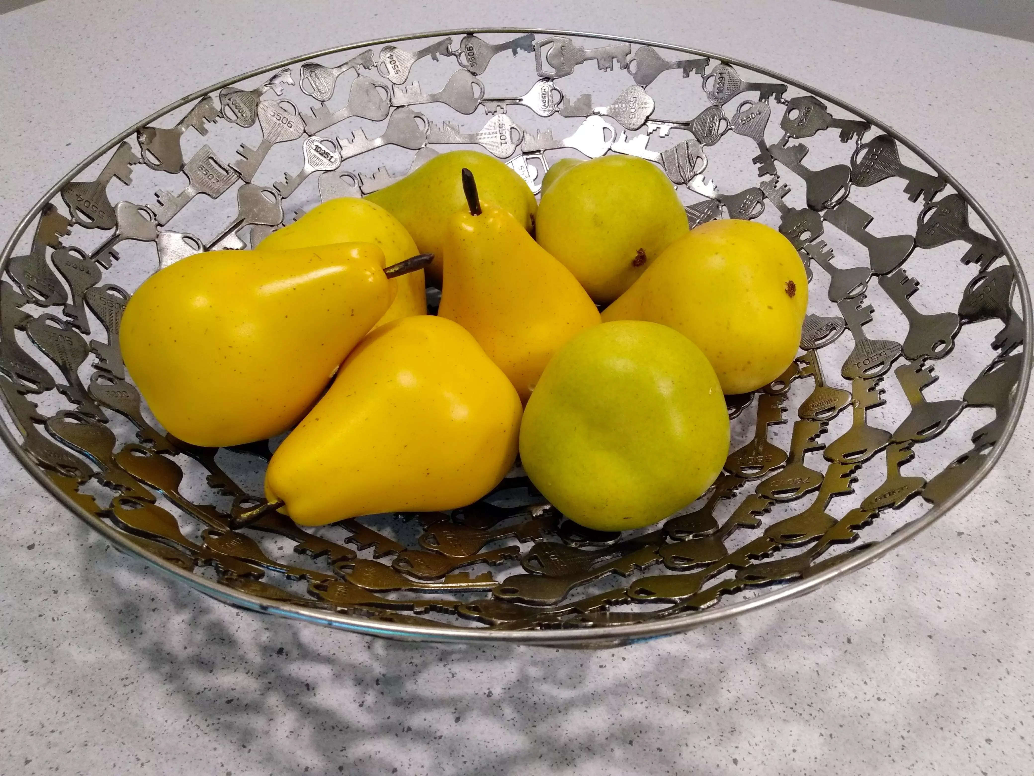 Plastic yellow pears in a silver fruit bowl