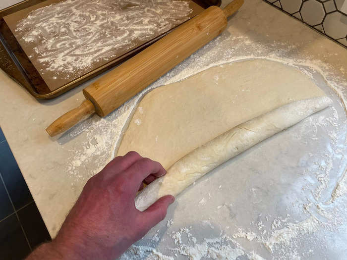 Flatten the dough balls out and roll them into long batons.