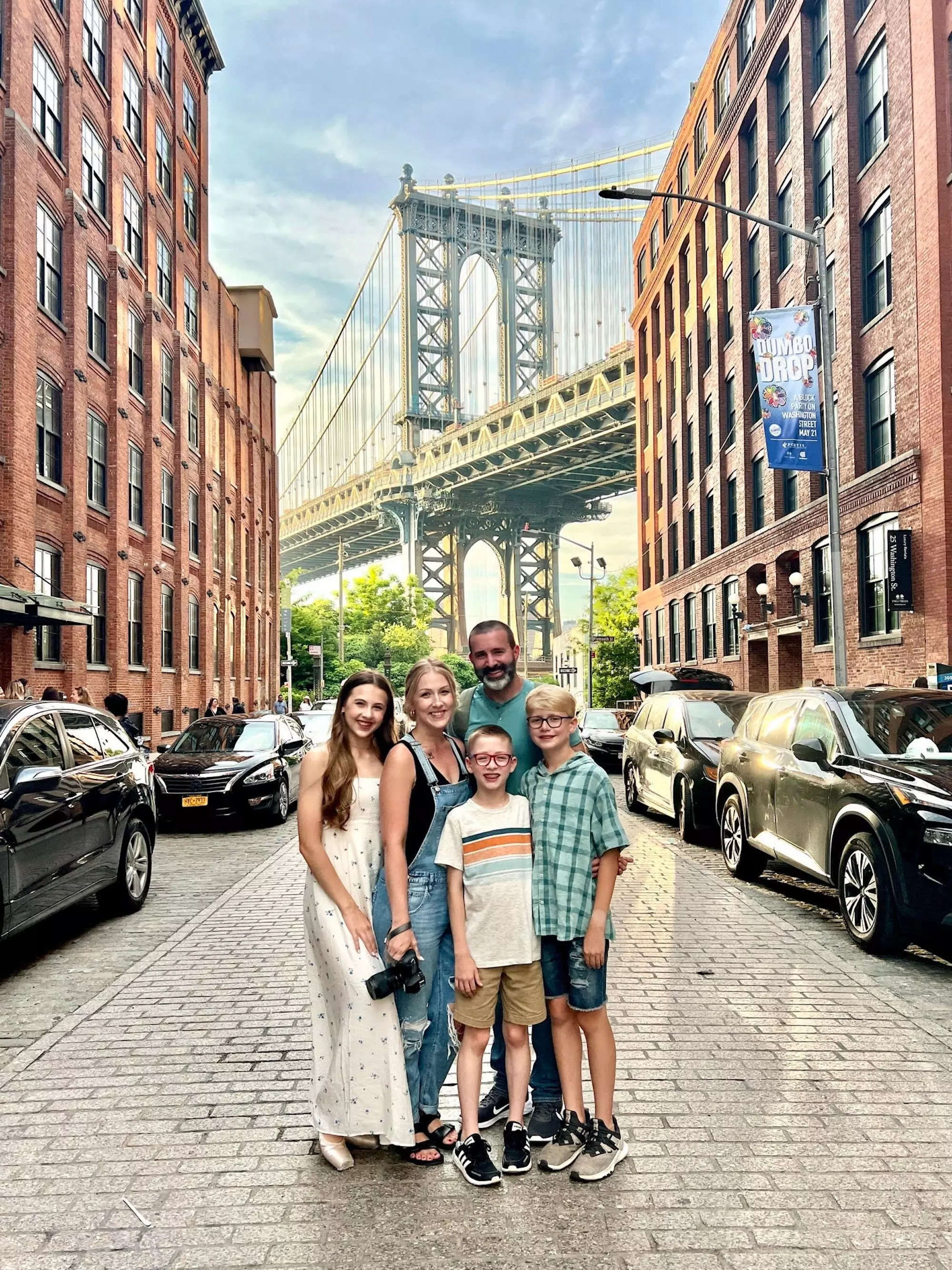 A family of five stand in front of the Brooklyn Bridge.