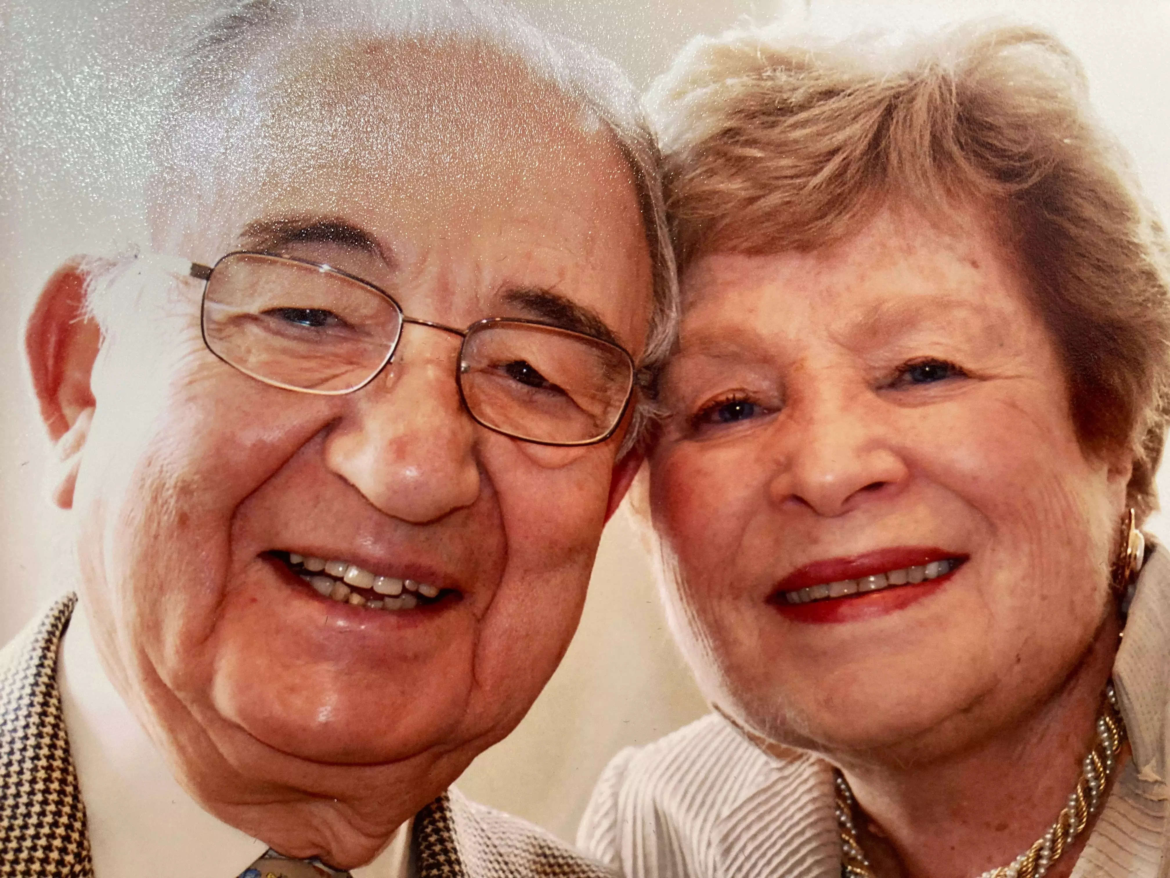 An older couple poses with their heads close together.