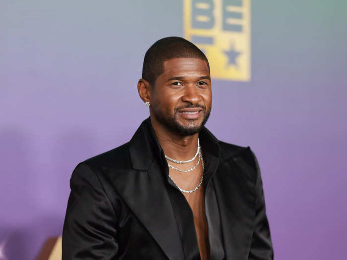 Usher, honored as Entertainer of the Year, wore a satin black suit and matching shirt unbuttoned to his waist and featured oversize cuffs. 