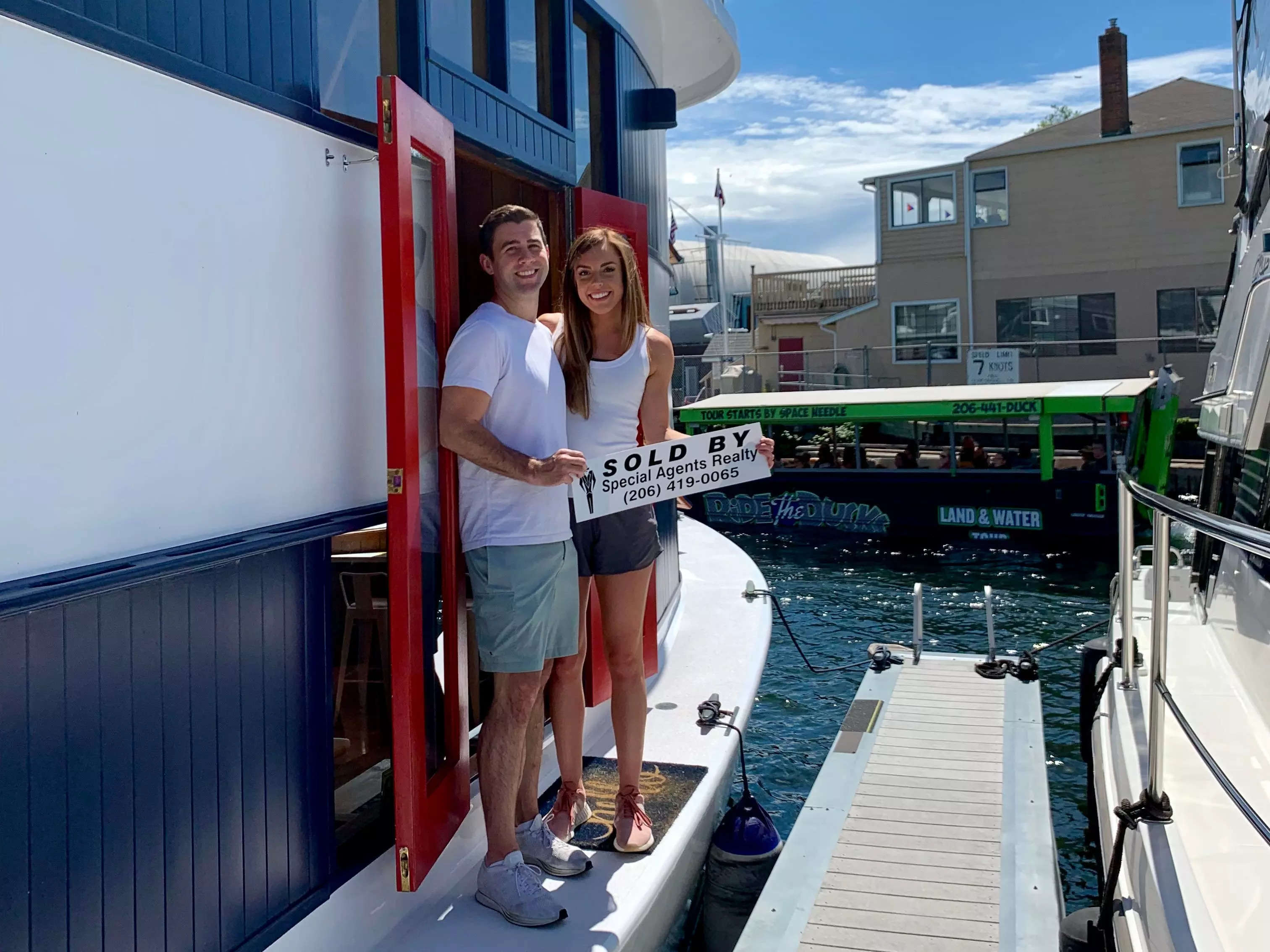 A man and a woman posing next to their houseboat.